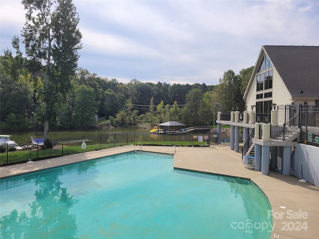 pool featuring stairway, fence, a patio area, and a wooded view