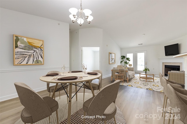 dining space with light hardwood / wood-style floors, lofted ceiling, and a chandelier