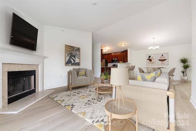 living room featuring a notable chandelier, a fireplace, and light hardwood / wood-style floors