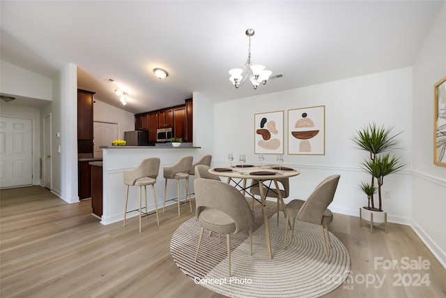 dining space featuring lofted ceiling, a chandelier, and light hardwood / wood-style flooring