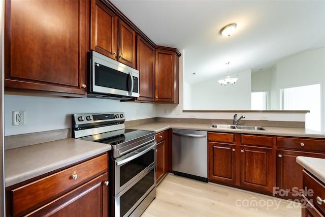 kitchen featuring appliances with stainless steel finishes, sink, lofted ceiling, light hardwood / wood-style flooring, and a chandelier