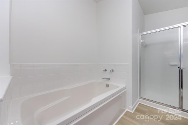 bathroom featuring hardwood / wood-style flooring and plus walk in shower