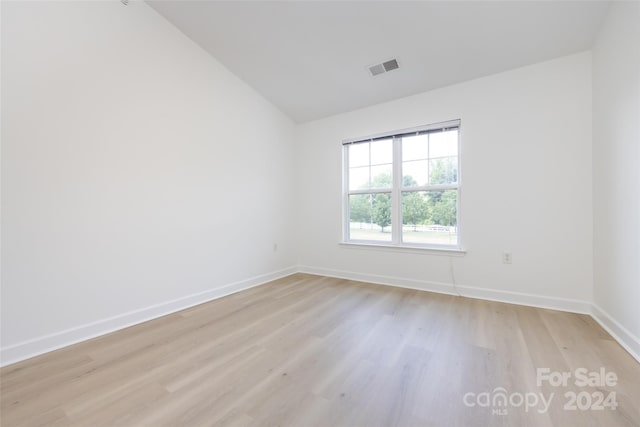 unfurnished room with lofted ceiling and light hardwood / wood-style flooring