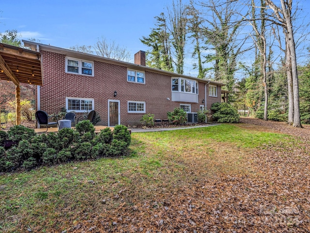 rear view of property with a patio, cooling unit, and a lawn