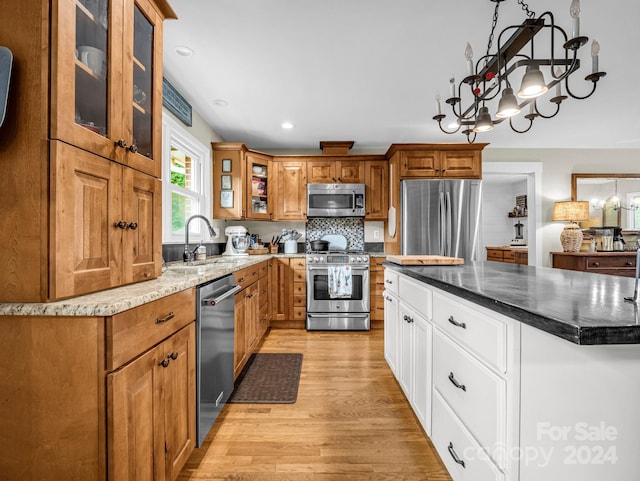 kitchen with backsplash, white cabinets, sink, appliances with stainless steel finishes, and light hardwood / wood-style floors