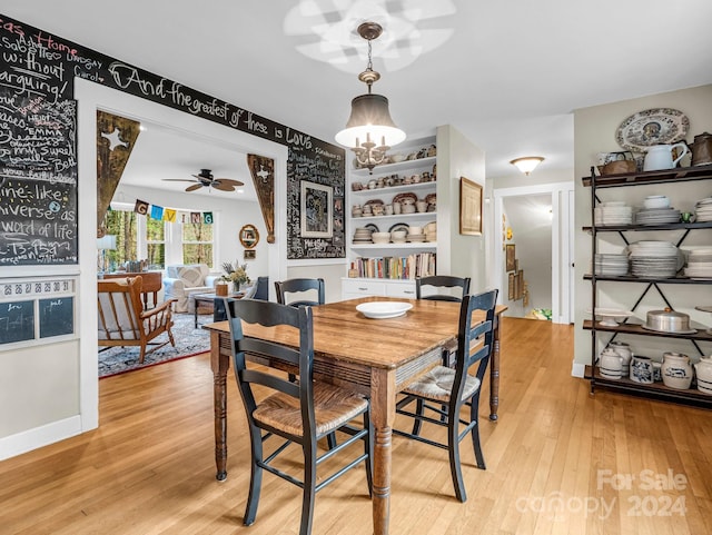 dining space featuring built in shelves, light hardwood / wood-style floors, and ceiling fan with notable chandelier