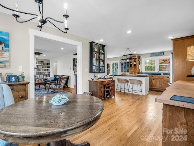 dining room with light hardwood / wood-style floors, an inviting chandelier, and sink