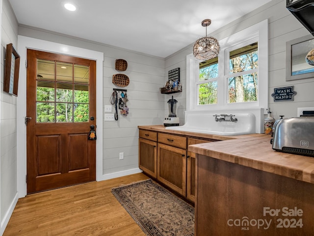 bar featuring butcher block counters, light hardwood / wood-style flooring, pendant lighting, and an inviting chandelier