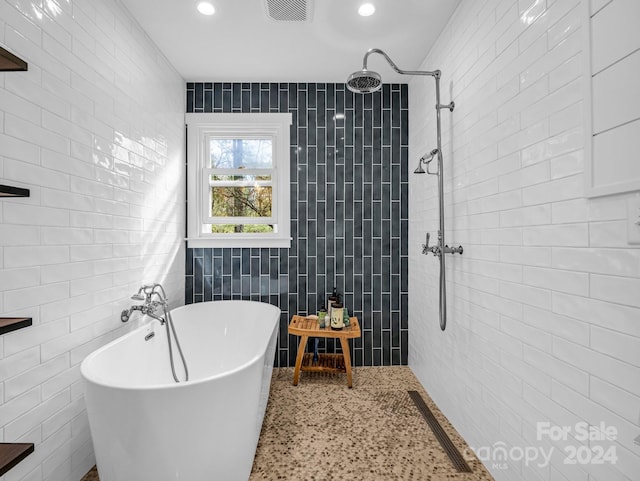 bathroom with shower with separate bathtub and tile walls