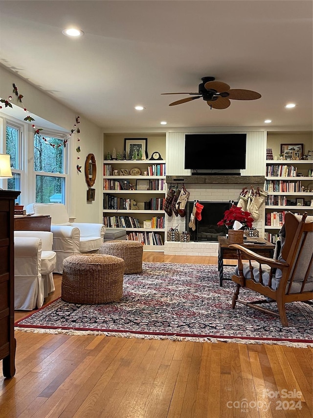 living room with hardwood / wood-style flooring, ceiling fan, and a brick fireplace