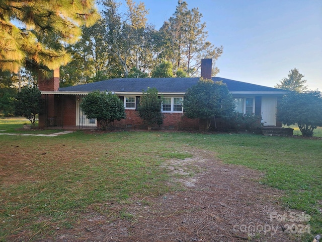 ranch-style home with a front lawn, a chimney, and brick siding