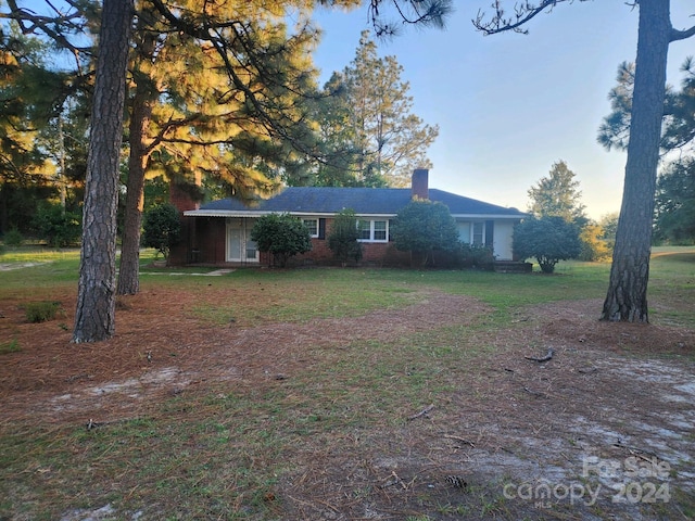 view of front of property featuring a front lawn, a chimney, and brick siding