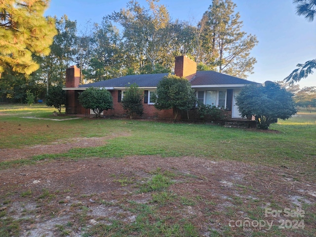 exterior space with brick siding, a front yard, and a chimney