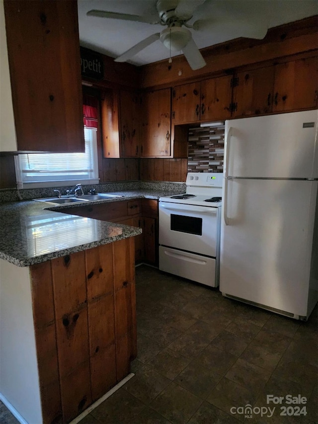 kitchen with brown cabinets, a sink, white appliances, decorative backsplash, and a peninsula