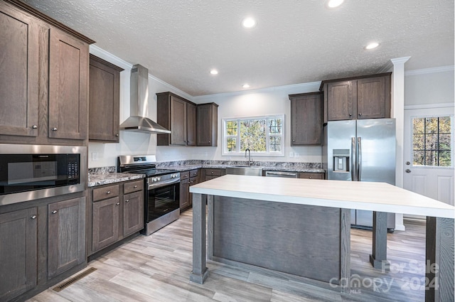 kitchen with plenty of natural light, wall chimney exhaust hood, stainless steel appliances, and sink