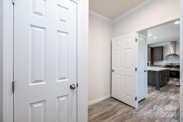 corridor featuring ornamental molding, a textured ceiling, and light wood-type flooring