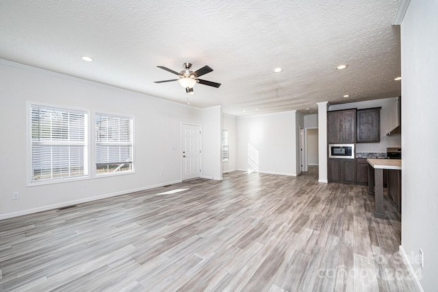 unfurnished living room featuring a textured ceiling, light wood-type flooring, ceiling fan, and ornamental molding