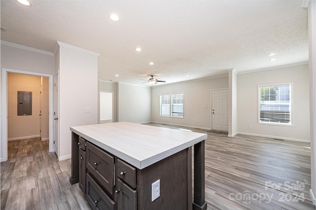 kitchen featuring ceiling fan, a kitchen island, ornamental molding, dark brown cabinets, and light hardwood / wood-style floors