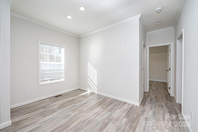 empty room with ornamental molding, a textured ceiling, and light wood-type flooring