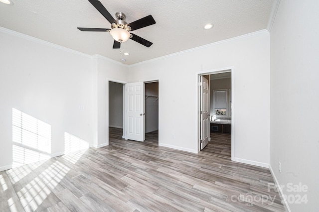 unfurnished bedroom featuring a closet, a spacious closet, light hardwood / wood-style flooring, and ceiling fan