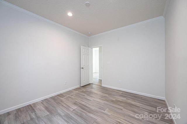 unfurnished room with a textured ceiling, light wood-type flooring, and crown molding