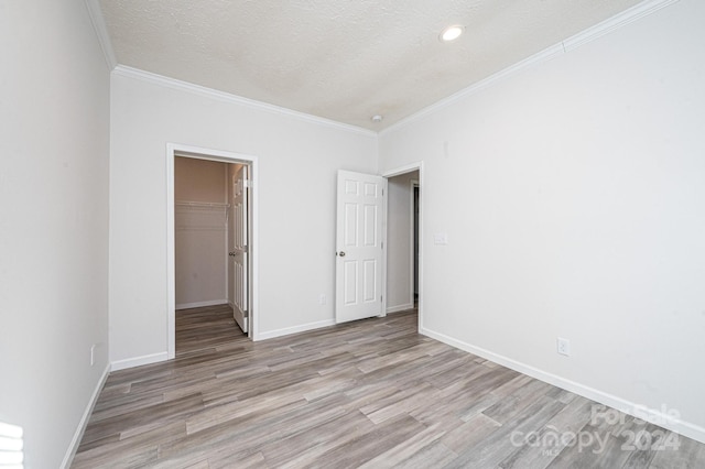 unfurnished room with a textured ceiling, light hardwood / wood-style flooring, and ornamental molding