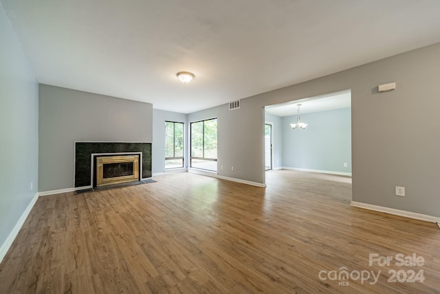 unfurnished living room with a chandelier, light hardwood / wood-style flooring, and a tiled fireplace