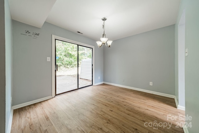 spare room featuring light hardwood / wood-style floors and a notable chandelier