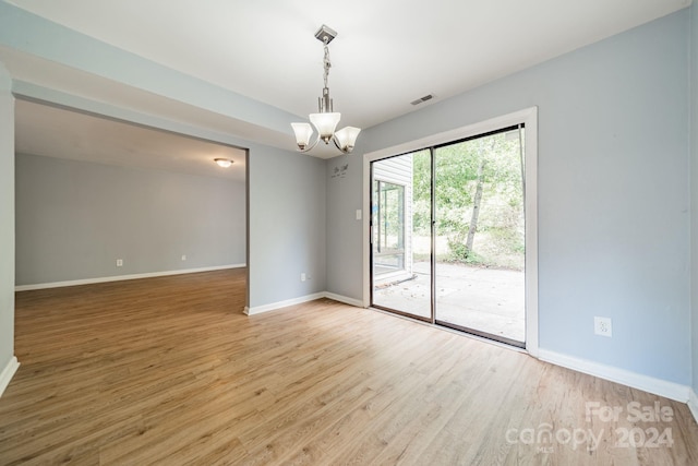 spare room featuring a notable chandelier and wood-type flooring