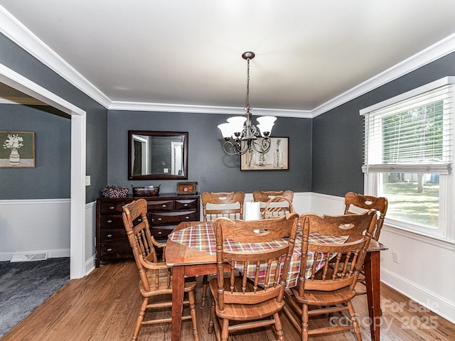 dining area with hardwood / wood-style flooring, a wealth of natural light, ornamental molding, and an inviting chandelier