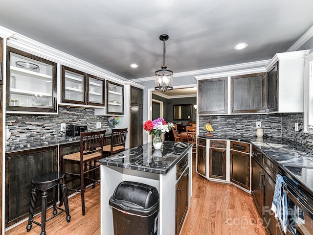 kitchen featuring light hardwood / wood-style floors, pendant lighting, a center island, ornamental molding, and dark brown cabinets