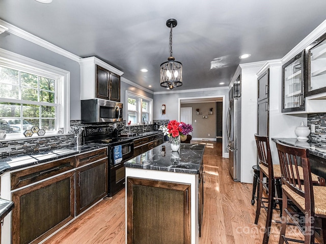 kitchen featuring appliances with stainless steel finishes, dark brown cabinets, a kitchen island, and tasteful backsplash