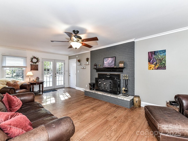 living room featuring hardwood / wood-style floors, ceiling fan, a brick fireplace, french doors, and ornamental molding