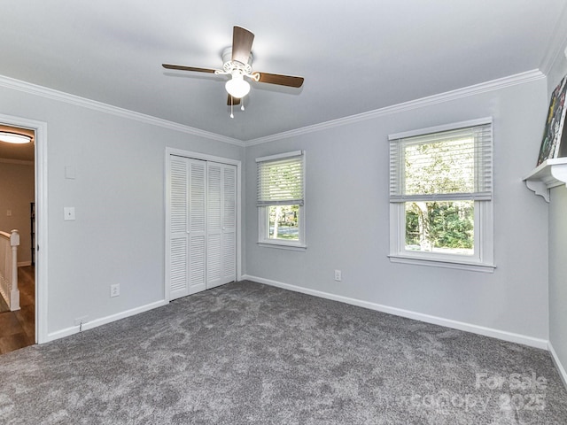 unfurnished bedroom with ceiling fan, a closet, crown molding, and dark colored carpet