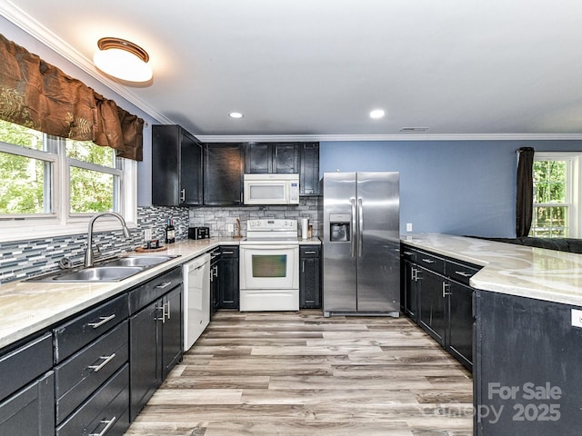 kitchen featuring light stone countertops, white appliances, light hardwood / wood-style floors, sink, and backsplash