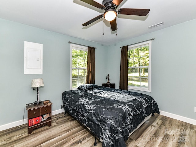 bedroom with ceiling fan, electric panel, and hardwood / wood-style floors