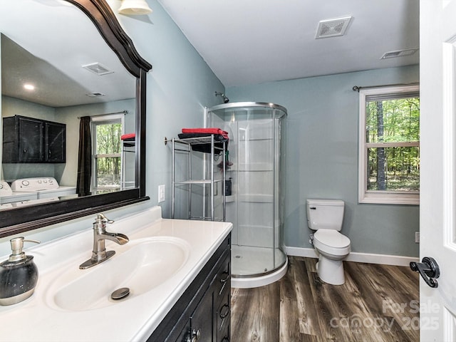 bathroom with toilet, vanity, washer / dryer, hardwood / wood-style flooring, and an enclosed shower