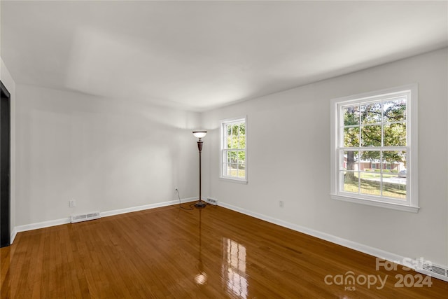 unfurnished room with hardwood / wood-style flooring and a healthy amount of sunlight