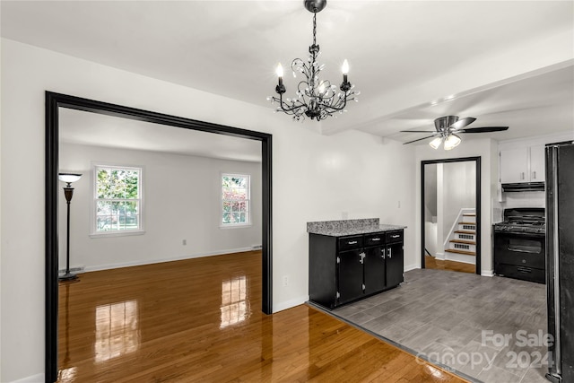 kitchen featuring white cabinetry, black gas stove, dark wood-type flooring, and ceiling fan with notable chandelier