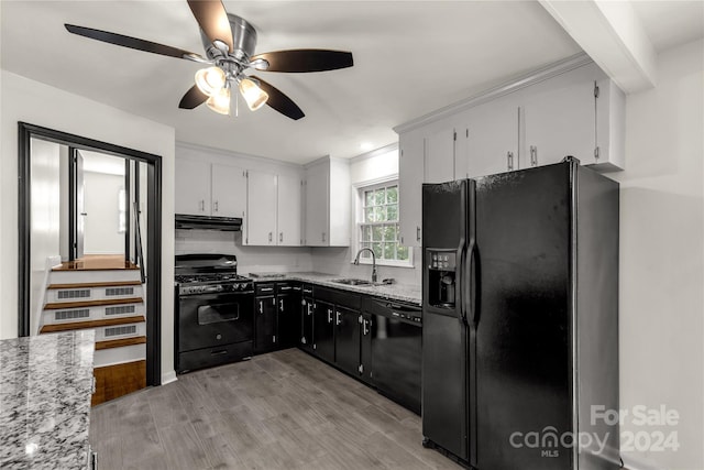 kitchen with decorative backsplash, white cabinets, black appliances, light hardwood / wood-style floors, and sink