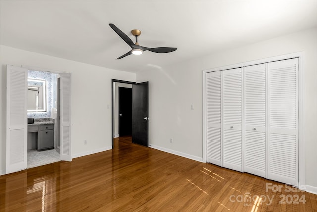 unfurnished bedroom featuring ensuite bathroom, hardwood / wood-style flooring, a closet, and ceiling fan