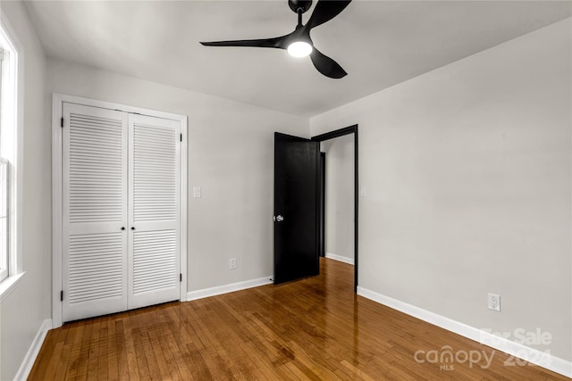 unfurnished bedroom with wood-type flooring, a closet, and ceiling fan