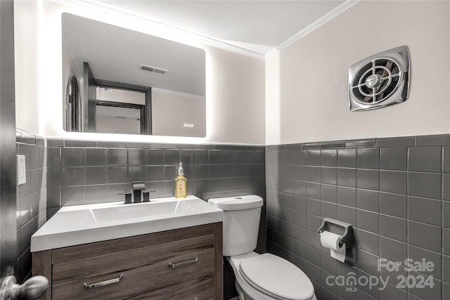 bathroom featuring vanity, toilet, crown molding, and tile walls