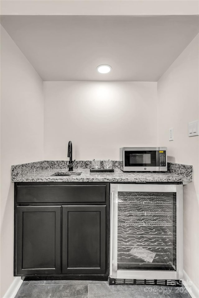 bar with sink, beverage cooler, and light stone counters