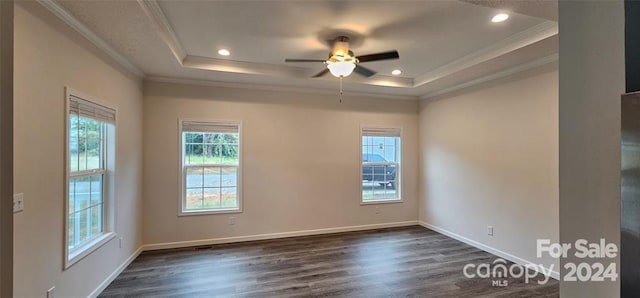 empty room with a tray ceiling, crown molding, ceiling fan, and dark wood-type flooring