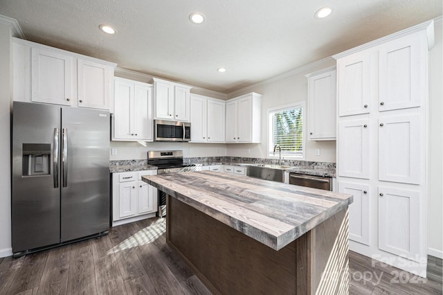 kitchen featuring sink, dark hardwood / wood-style flooring, crown molding, white cabinets, and appliances with stainless steel finishes