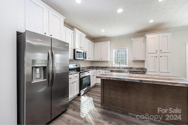 kitchen featuring crown molding, dark hardwood / wood-style flooring, white cabinets, and stainless steel appliances