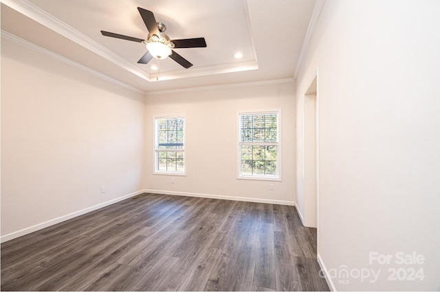 spare room featuring a raised ceiling, ceiling fan, dark hardwood / wood-style flooring, and ornamental molding