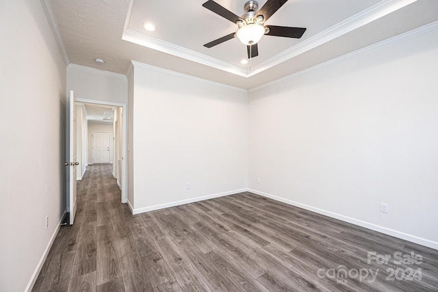 spare room with a raised ceiling, crown molding, ceiling fan, and dark wood-type flooring