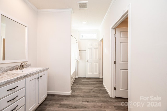 bathroom featuring hardwood / wood-style floors, a bathtub, crown molding, and vanity